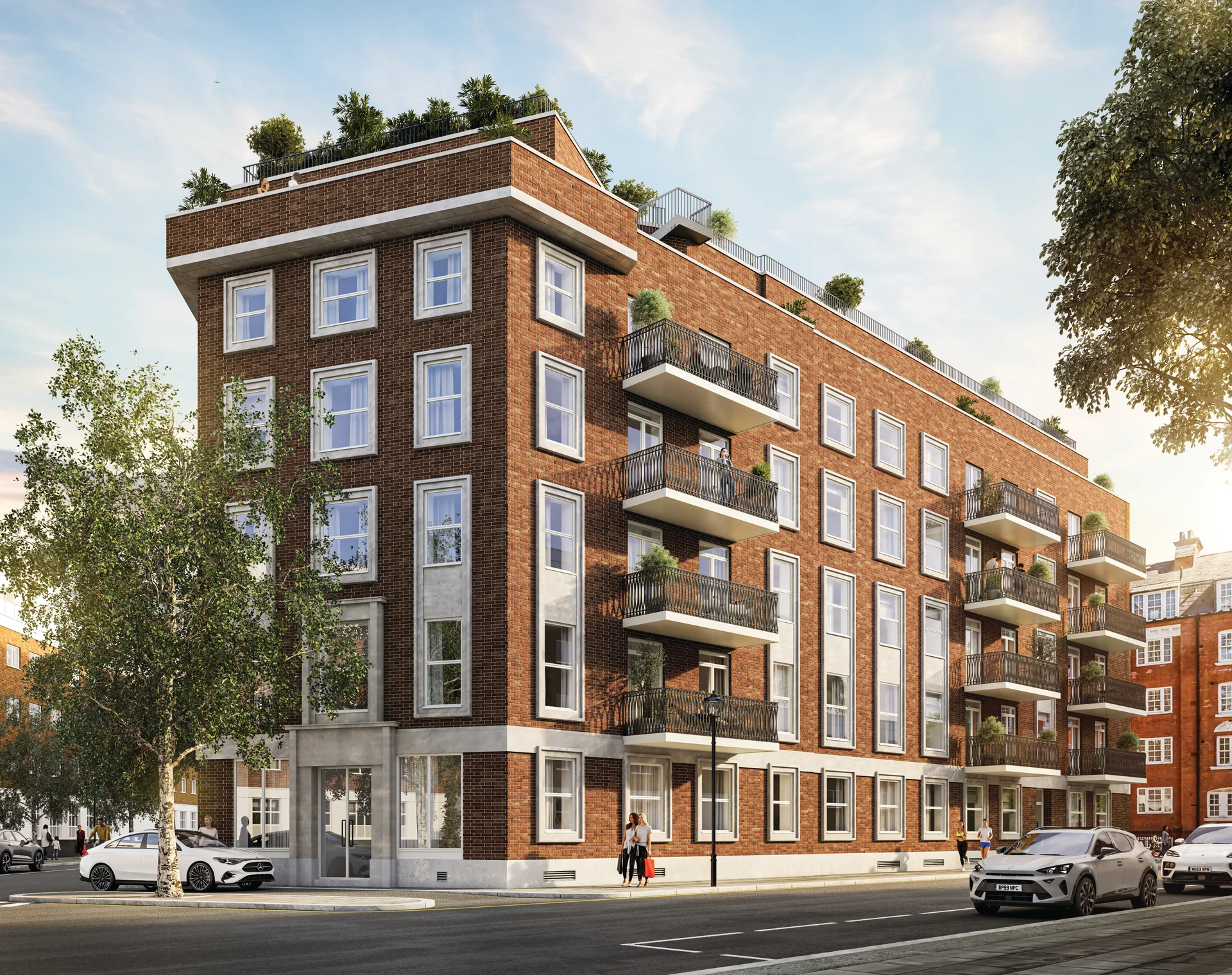 Red-brick residential apartment building with balconies, rooftop planting and street-level views on a sunny city street.